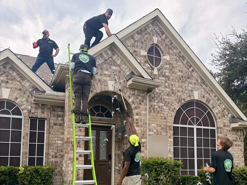 Real photo: QuietScapes crew installing lights on a brick home during the day