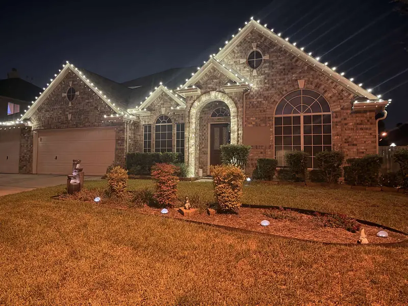 Real photo: the same brick home at night with warm white C9 lights on