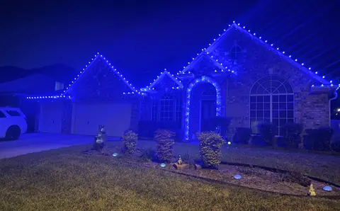 Solid blue C9 lights on a brick home's roofline and arched entry