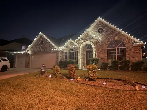 Warm white roofline lights on a brick home